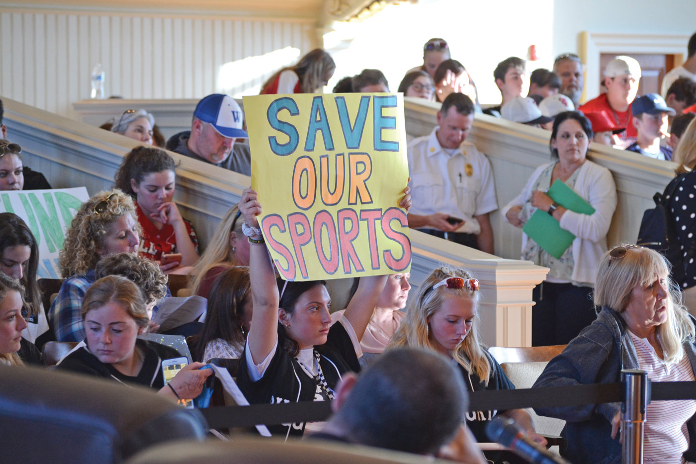 SAVE THE SPORTS: A Pilgrim High School student athlete encompasses the student position with a sign reading “Save Our Sports”